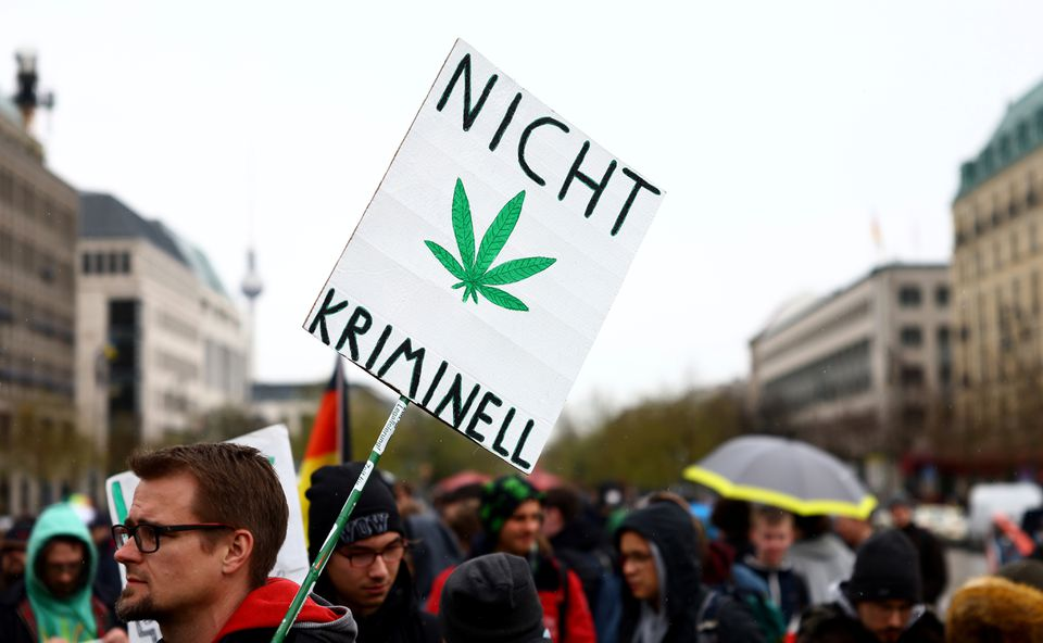 A man carries a sign reading "Not criminal" as he participates in a gathering with marijuana activists to mark the annual world cannabis day and to protest for legalization of marijuana, in front of the Brandenburg Gate, in Berlin, Germany, April 20, 2022. REUTERS/Lisi Niesner/File Photo