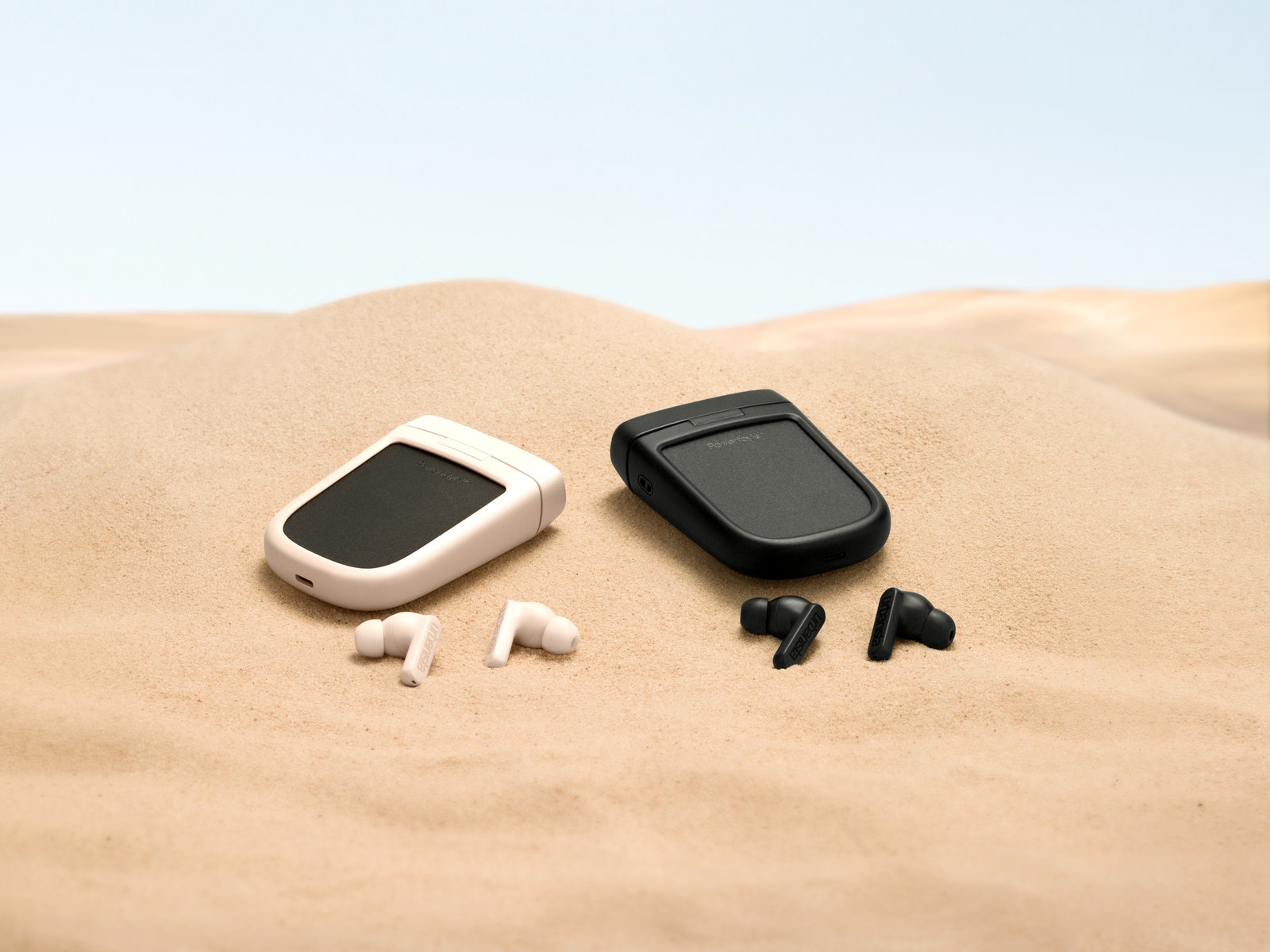 Urbanista Phoenix earbuds and charging case lying on sand