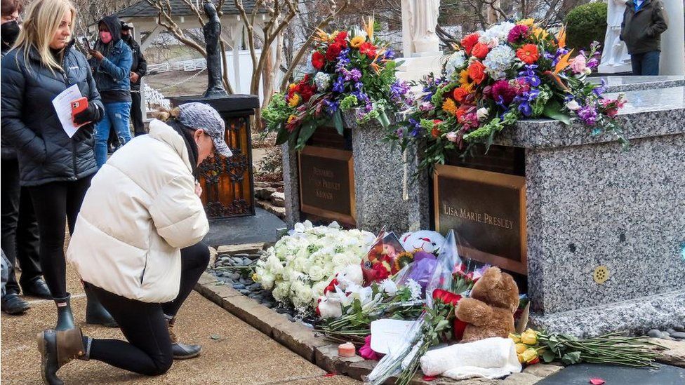 A fan kneels at Lisa Marie Presley's grave