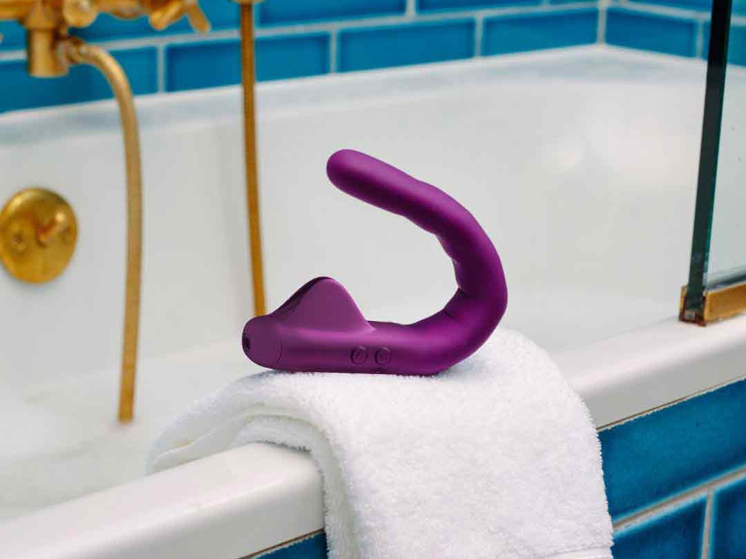 MysteryVibe Crescendo sex toy placed on a towel near the edge of a bathtub