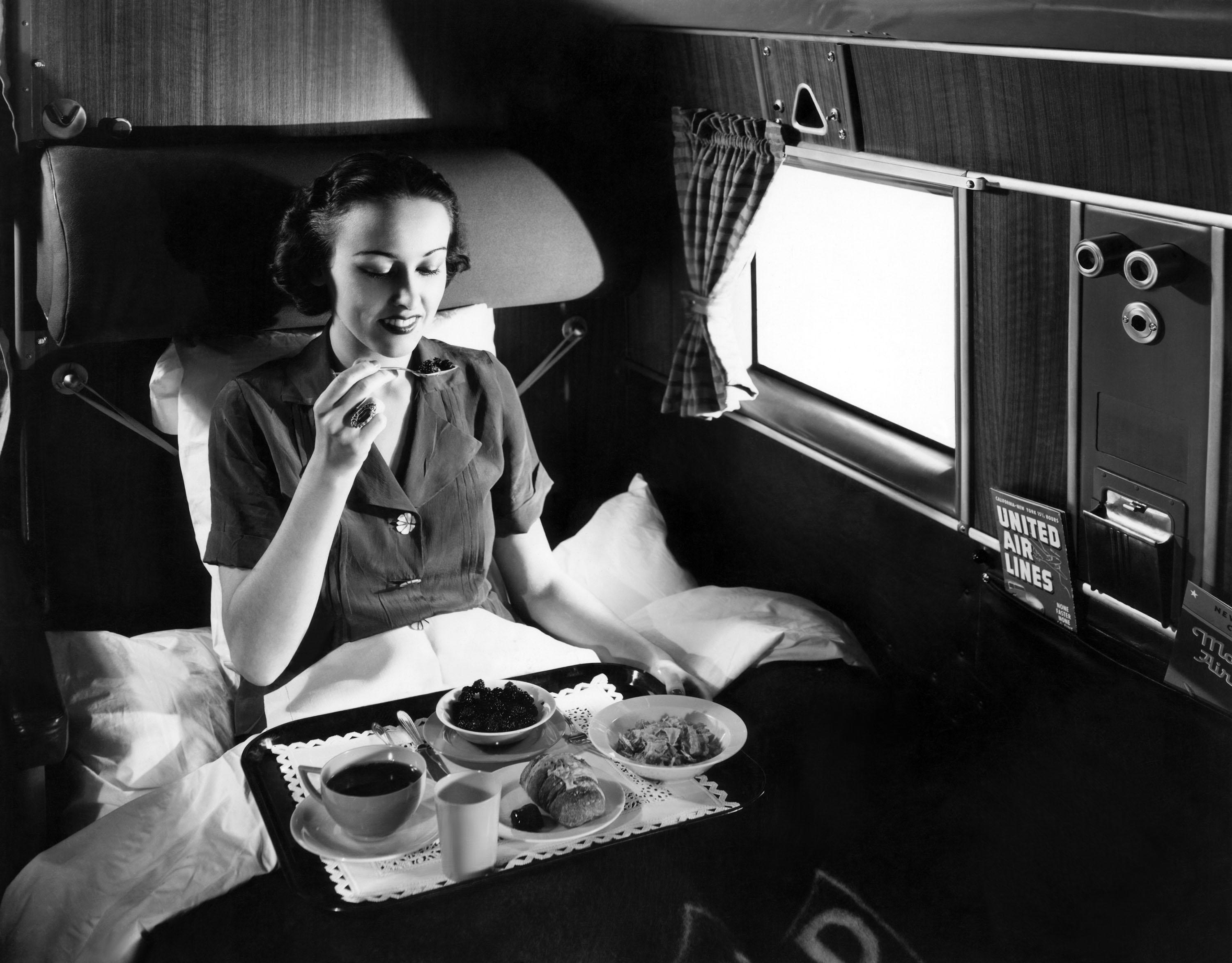 A passenger eats breakfast on United Airline's Douglas Mainliner Sleeper airplane from Chicago to San Francisco in 1937
