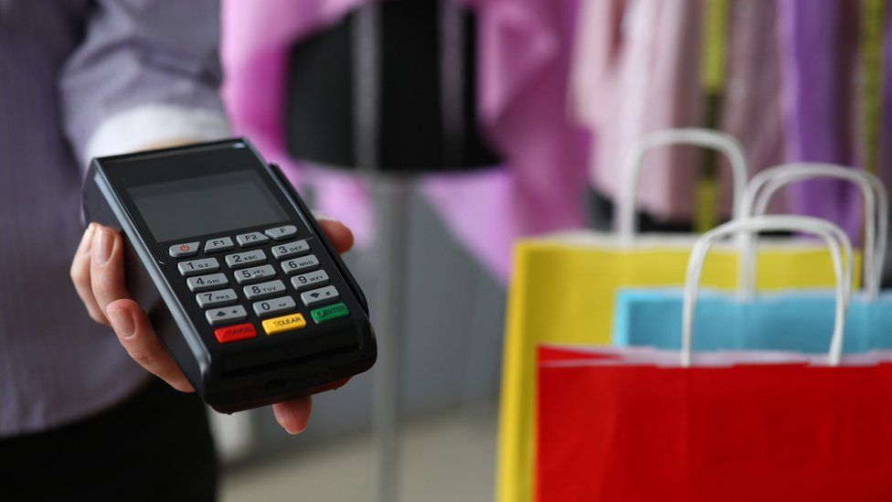 Shop worker holds out chip and PIN payment card reader