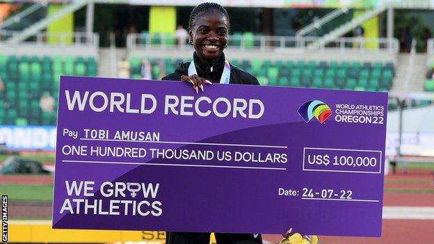 Tobi Amusan with a cheque for $100,000 after setting a new world record in the 100m hurdles at the World Athletics Championships in Eugene