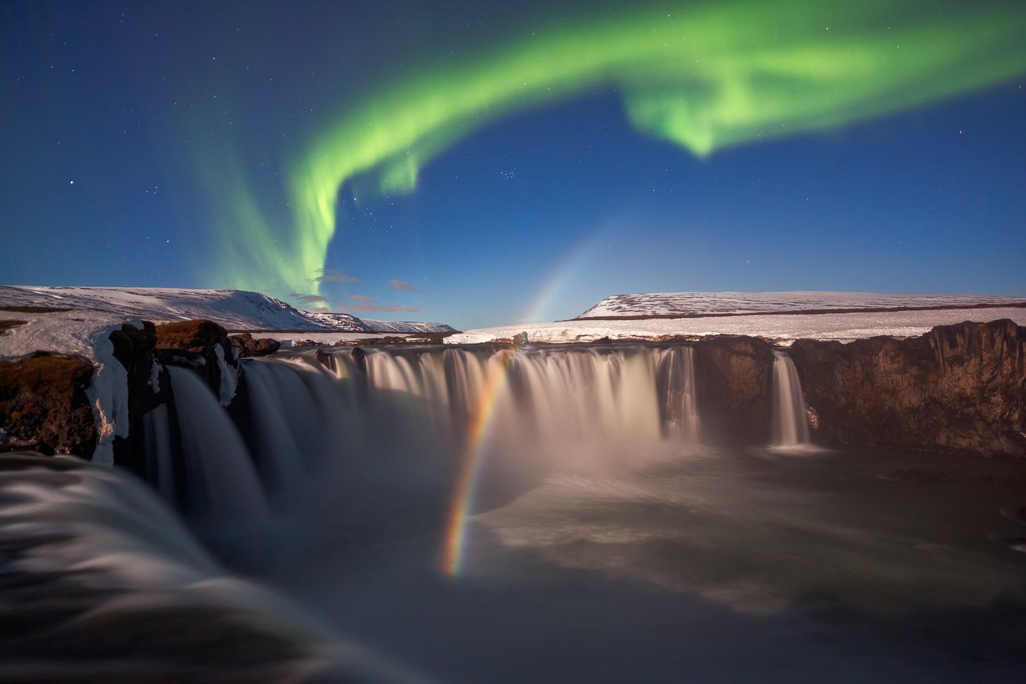 The Northen Lights and a lunar rainbow seen above the Godafoss waterfall in Iceland.