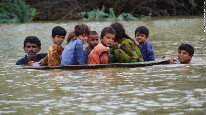 A man helps children navigate floodwaters using a satellite dish in Balochistan, Pakistan, on Friday, August 26.