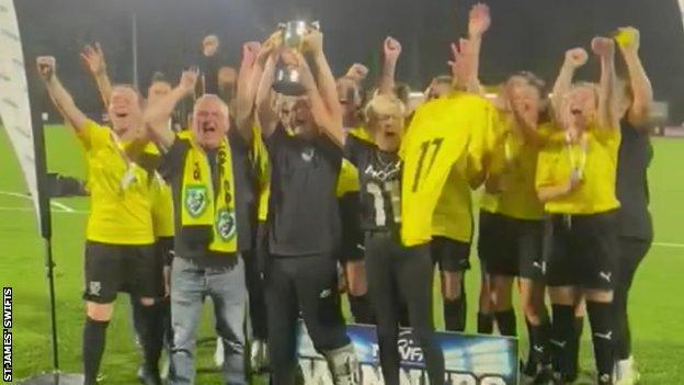 Molly White's mother, father and brother lift the trophy