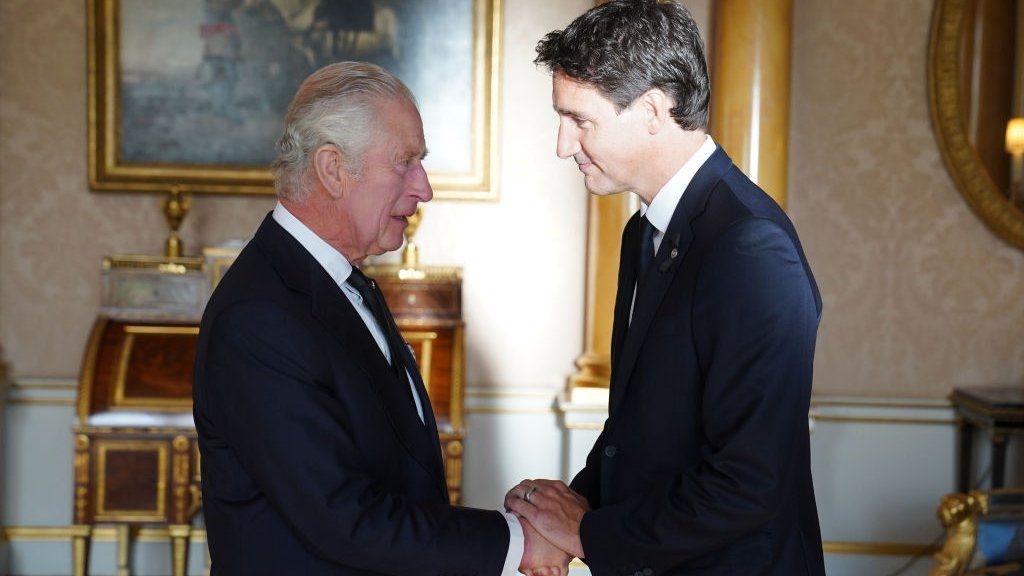 Prime Minister Justin Trudeau shakes hands with King Charles III at Buckingham Palace.