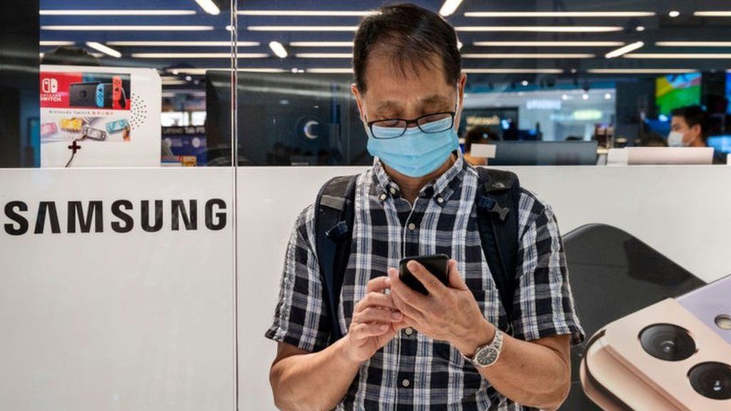 A man stands in front of a store selling Samsung phones in Hong Kong.