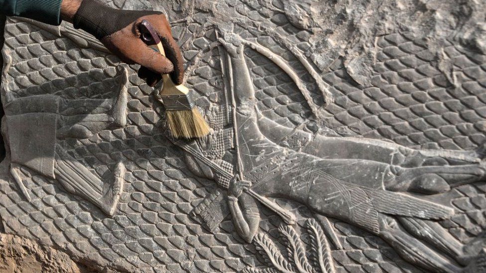 An Iraqi worker excavates a rock-carving relief found at the Mashki Gate, from the ancient Assyrian city of Nineveh, on the outskirts of today's Mosul, 19 Oct 22