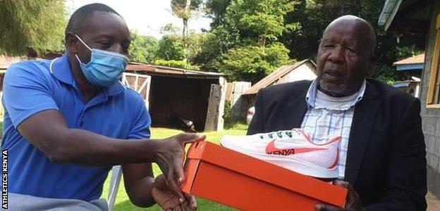 Wilson Kiprugut (right) is presented with a special pair of shoes by Athletics Kenya