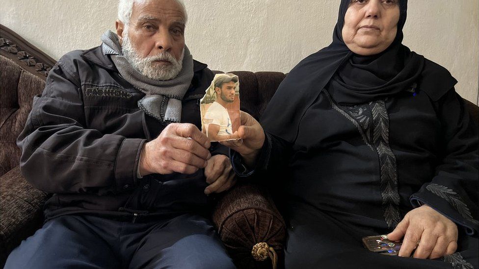 Mahdi and Umm Saif hold up a photograph of their son, Bakr