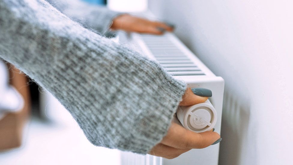 A woman adjusts a radiator