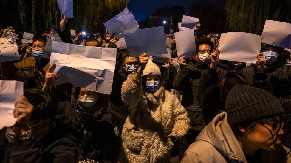 Demonstrators in Beijing hold blank pieces of paper