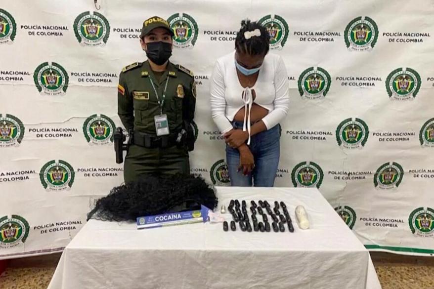 One of the suspects pictured alongside the drugs and hair extensions used for the smuggling operation.