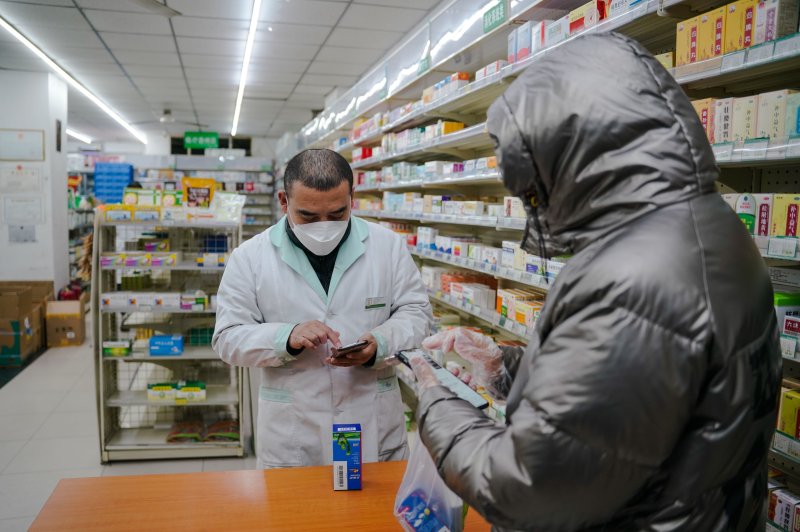 A staff member talks to a customer in a pharmacy in Beijing, China, on Friday. People anticipating a winter wave are buying more medicines causing a reportedly shortage of cold and flu medicines across China, as well as home remedies including canned yellow peaches. Photoi by Wu Hao/EPA-EFE