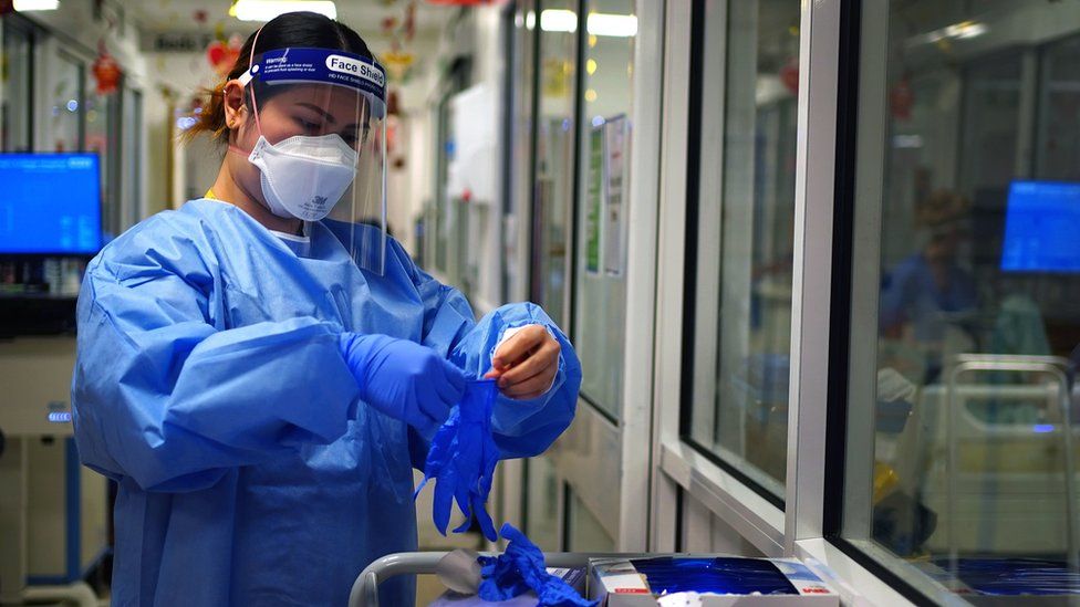 A member of staff puts on PPE at King's College Hospital in London