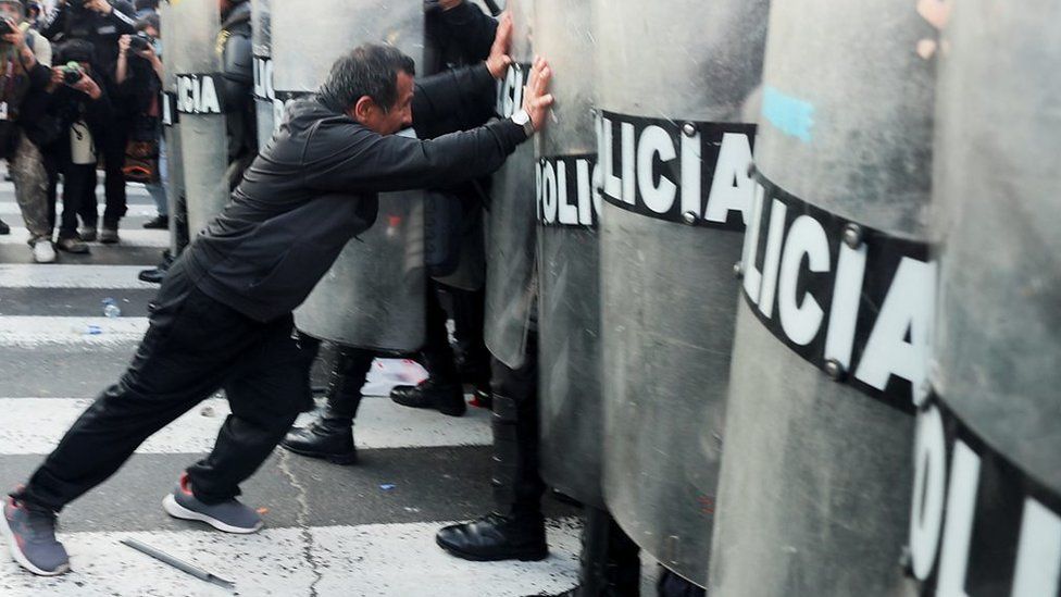 A man pushing against police shields
