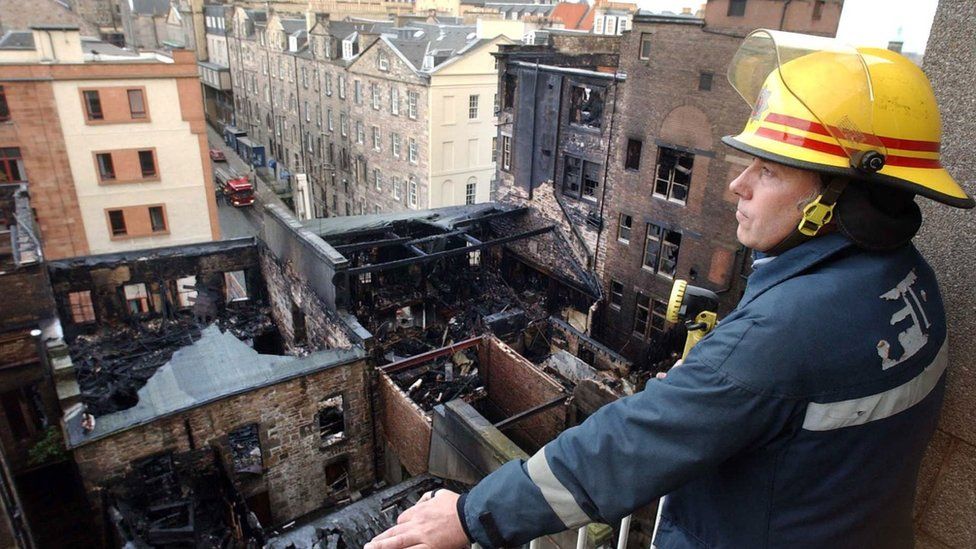A firefighter surveys the remains of the site looking towards the Cowgate and Blair Street