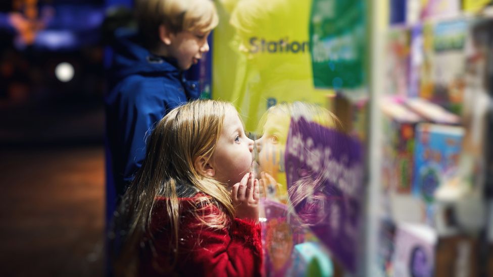 Children look at toys in a shop window at Christmas