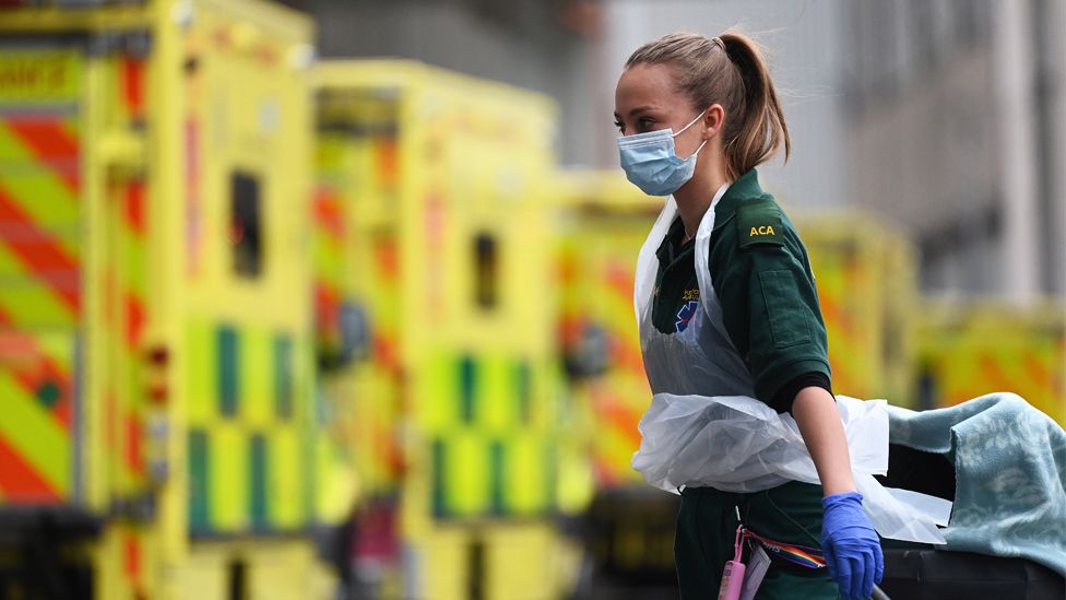 Female NHS ambulance staff member outside a hospital