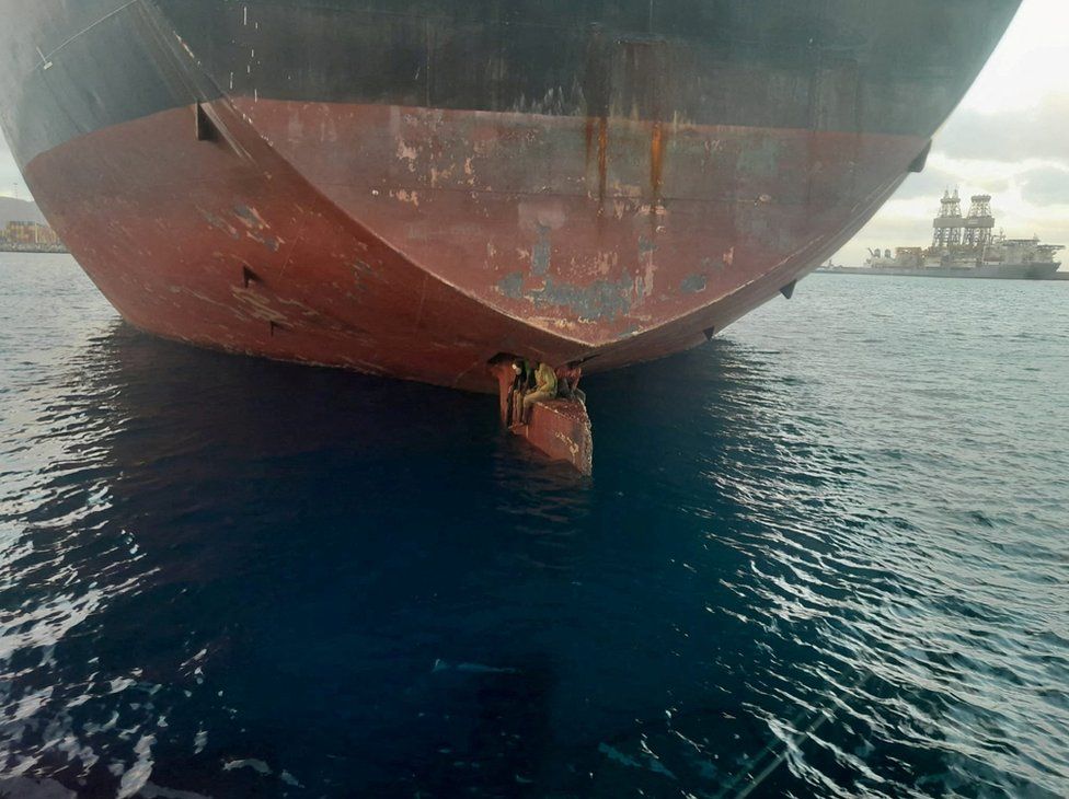 Three stowaway migrants are seen on the rudder blade of petrol vessel Althini II after traveling from Nigeria and before being rescued by Spanish coast guard, in this picture released on the Salvamento Maritimo official Twitter account, at sea near Las Palmas de Gran Canaria port, in the Canary Islands, Spain November 28, 2022.
