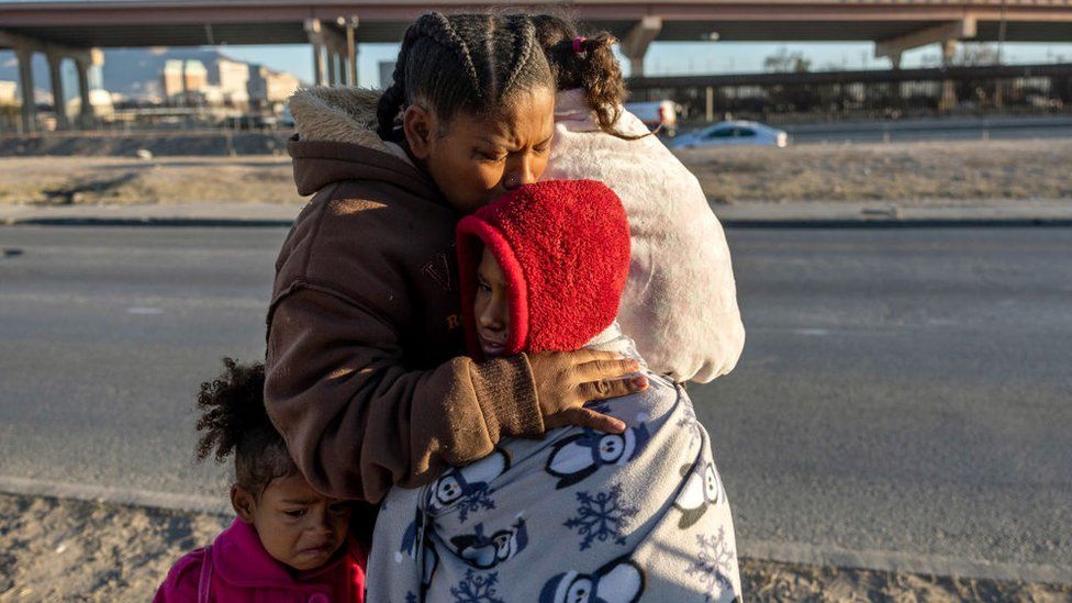 Venezuelan immigrant Yaneisi Martinez weeps while embracing her three children after Texas National Guard troops and state police blocked a popular border crossing area on December 20, 2022 in Ciudad Juarez, Mexico