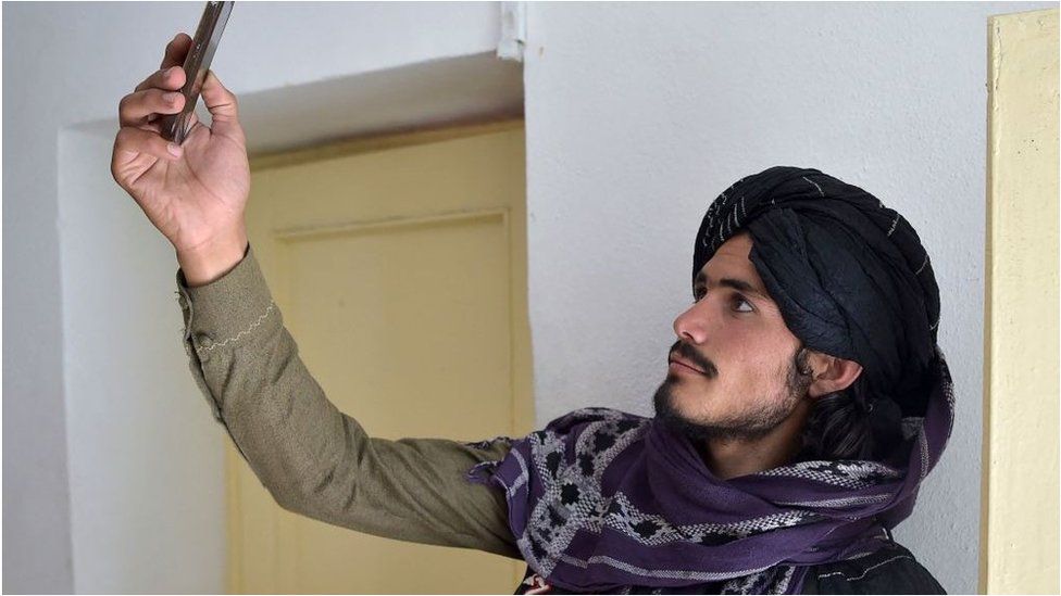 A Taliban fighter searches for a network signal for his mobile phone at a hospital.
