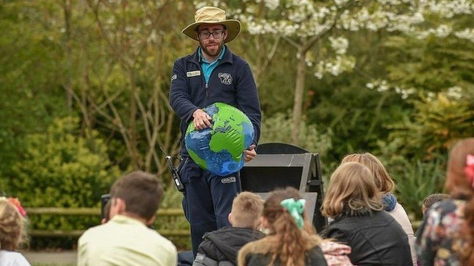 Chester Zoo worker holding inflatable globe teaching children