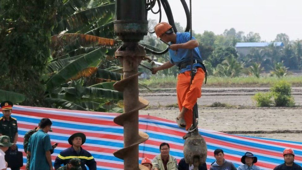 A long metal pipe is used to try to rescue the boy