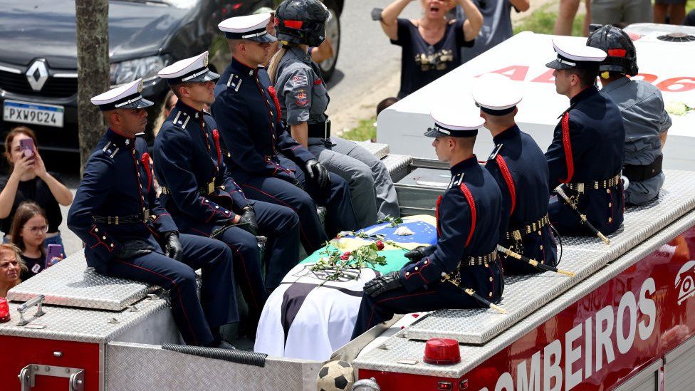 Pele's coffin is taken through the streets of Santos on a fire engine