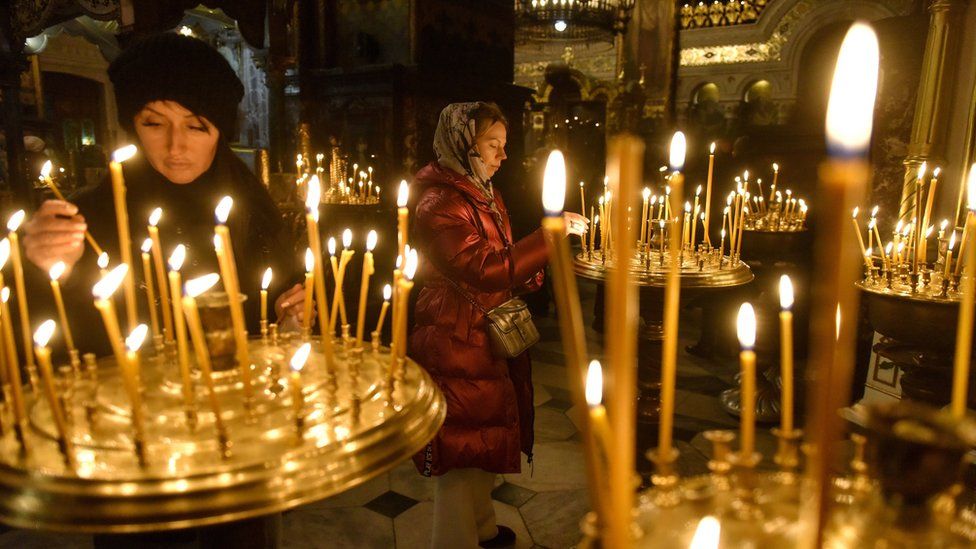 Ukrainian women light candles during a service