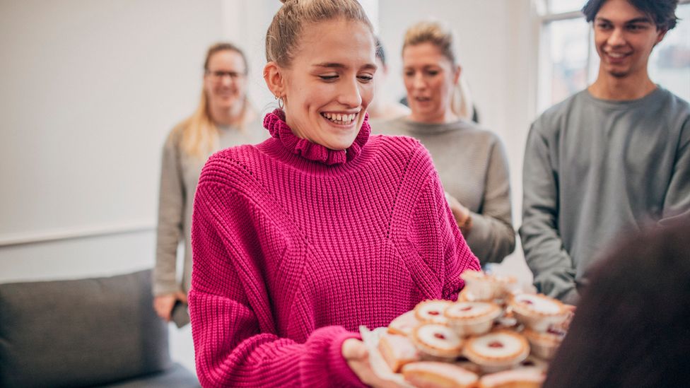 Woman offers cake in an office (stock photo)