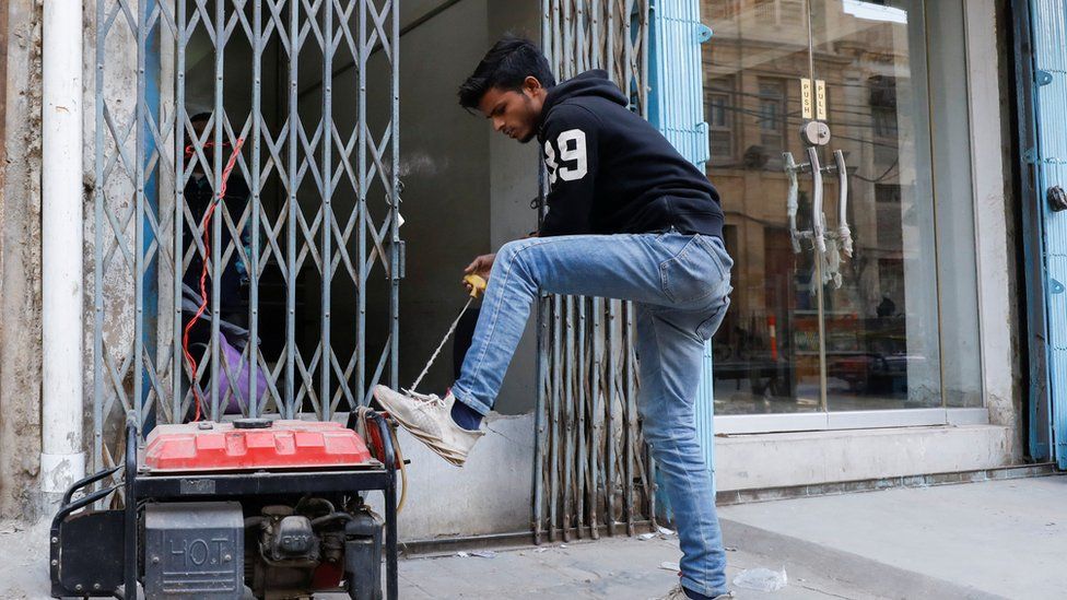 A man starts a generator outside his shop in Karachi, Pakistan