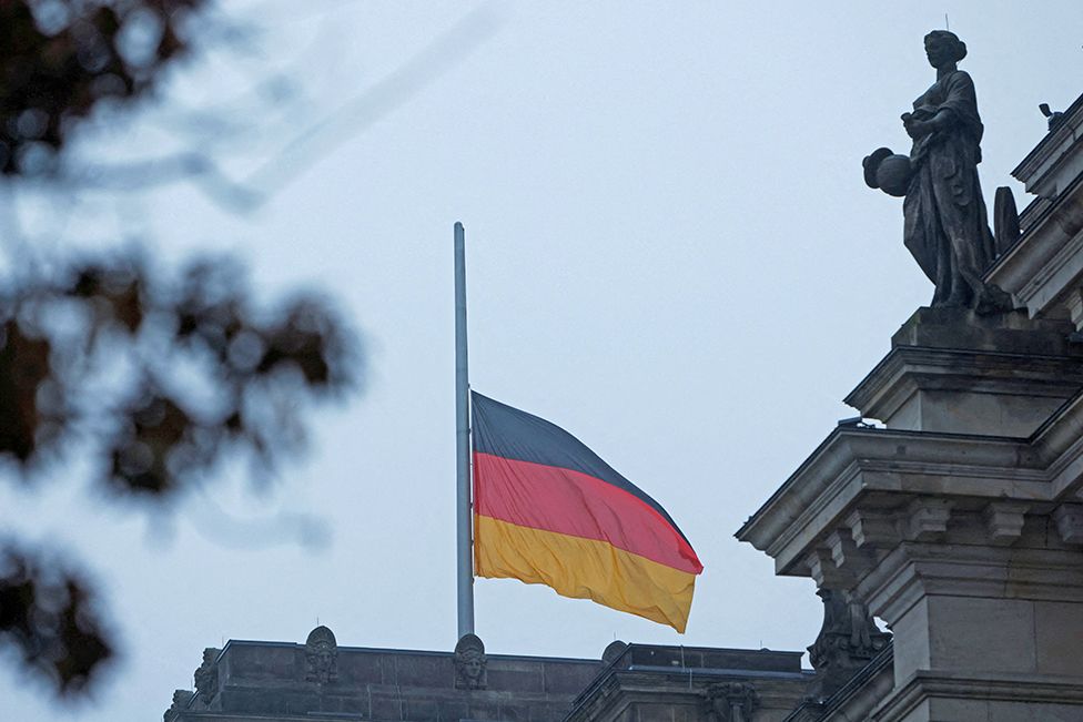 The German national flag flies at half mast outside the Bundestag on 27 January 2023