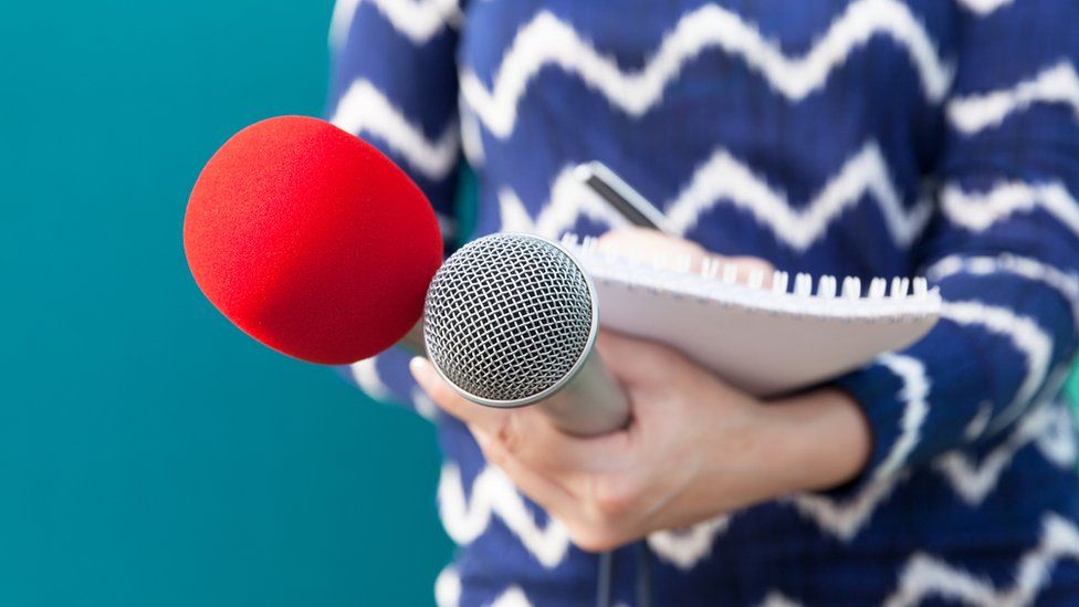 Midsection Of Journalist Holding Microphone And Book - stock photo