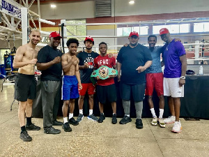 Dogboe holding his belt surrounded by his team at the gym