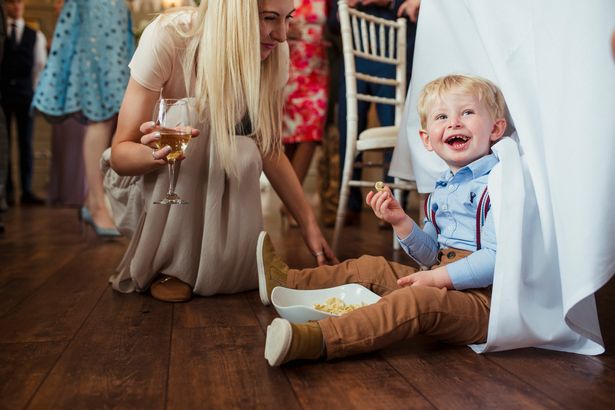 Young boy sitting under a table at a wedding reception