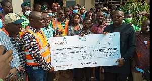 A Ghana Gas official (left) hands over a cheque to Prestea Bogoso MCE