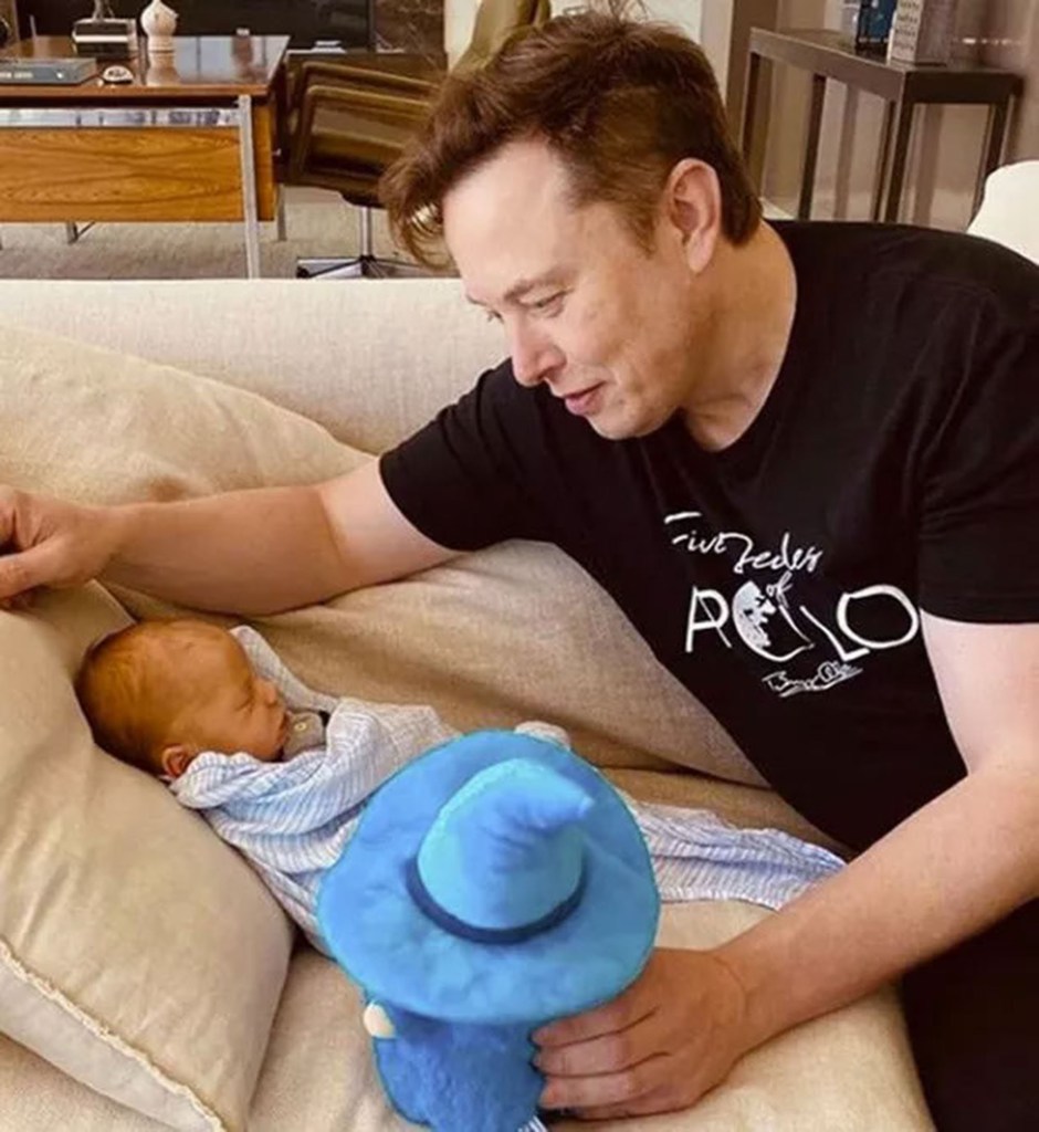 elon musk looking over his baby boy on a couch