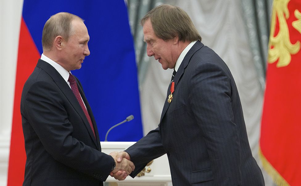 Vladimir Putin (L) shakes hands with Russian cellist Sergei Roldugin during an awarding ceremony at the Kremlin in Moscow on September 22, 2016